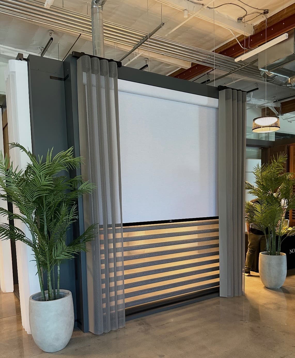 Custom window coverings on display: sheer drapery, a roller shade, and layered wood-tone shades.